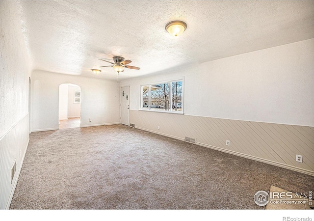 empty room featuring carpet, ceiling fan, and a textured ceiling