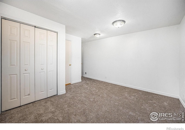 unfurnished bedroom with a textured ceiling, carpet floors, and a closet