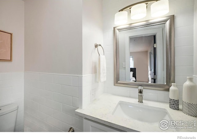 bathroom with vanity, tile walls, and toilet