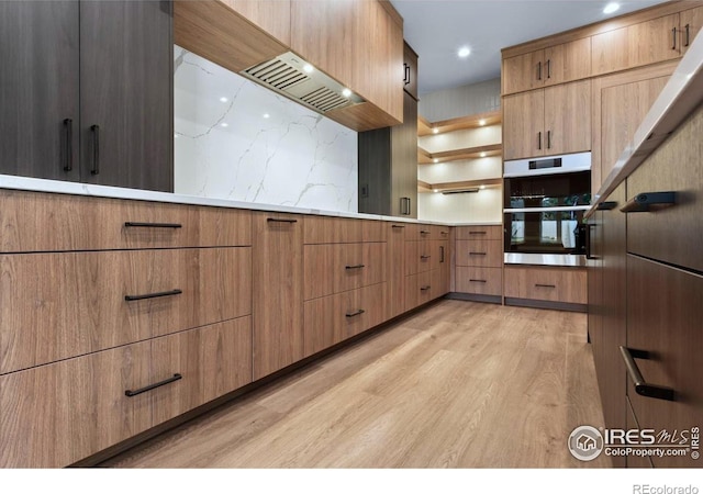 kitchen with backsplash, light hardwood / wood-style flooring, and stainless steel double oven