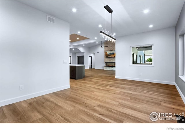 unfurnished living room with a fireplace, light hardwood / wood-style floors, and ceiling fan