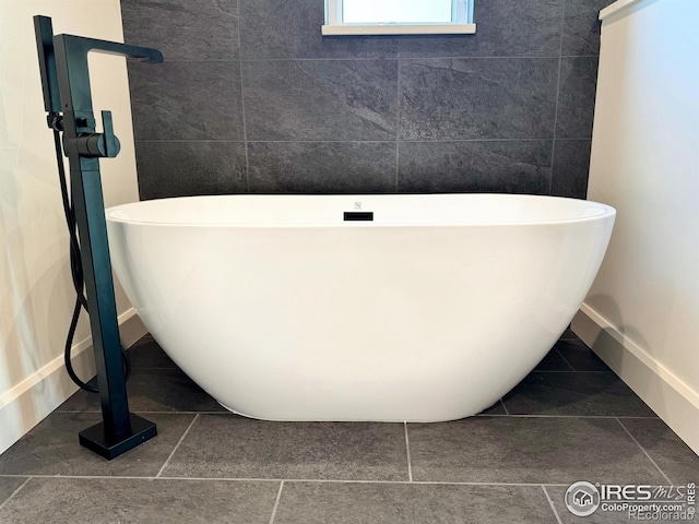 bathroom with tile patterned floors, a washtub, and tile walls