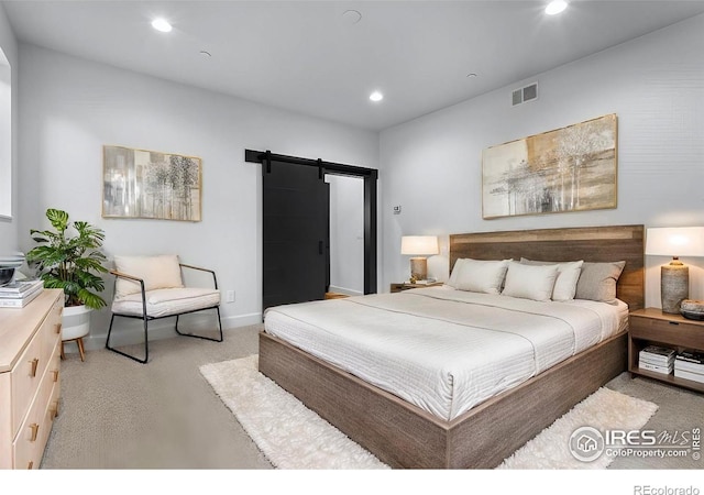 bedroom with a barn door and light carpet