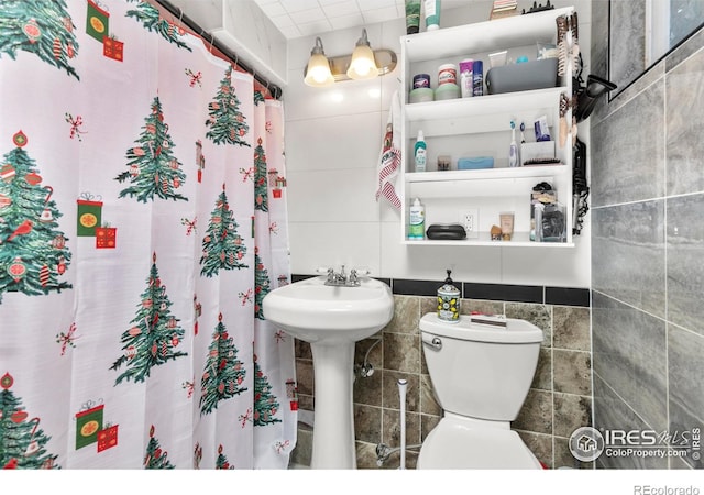 bathroom featuring a shower with curtain, toilet, and tile walls