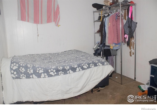 bedroom featuring wood walls and carpet