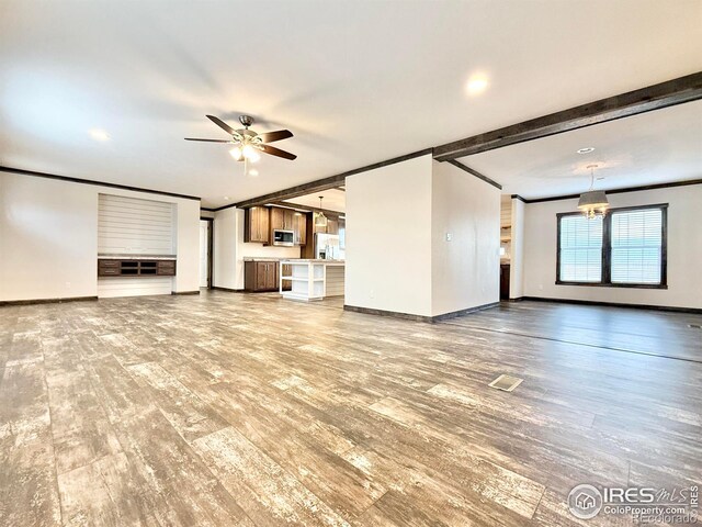 unfurnished living room with beam ceiling, ceiling fan, hardwood / wood-style floors, and crown molding