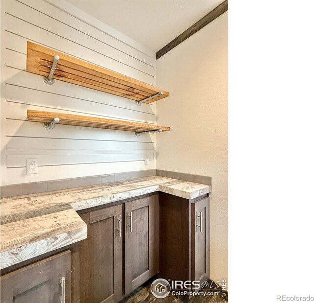 bar with dark brown cabinetry and ornamental molding