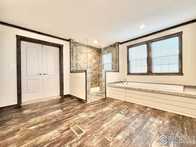 bathroom featuring wood-type flooring, ornamental molding, and plus walk in shower