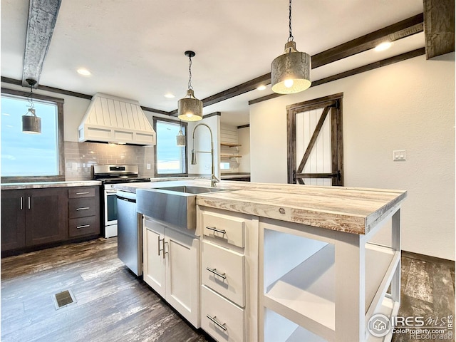 kitchen featuring beamed ceiling, plenty of natural light, a center island with sink, and custom range hood