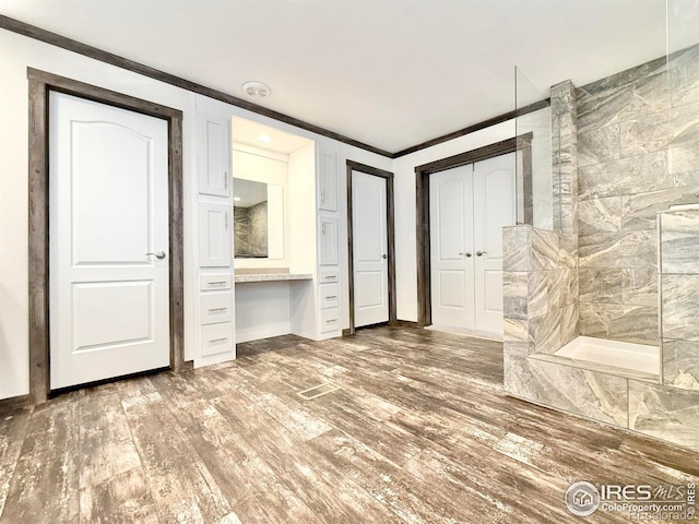 interior space with hardwood / wood-style floors, a shower, and crown molding