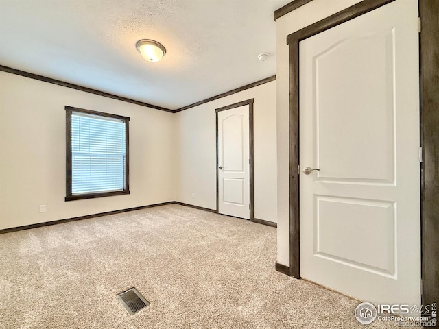 unfurnished bedroom featuring light carpet, crown molding, and a textured ceiling