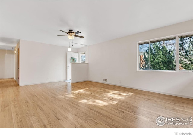 unfurnished room with visible vents, a ceiling fan, light wood-style floors, baseboards, and attic access