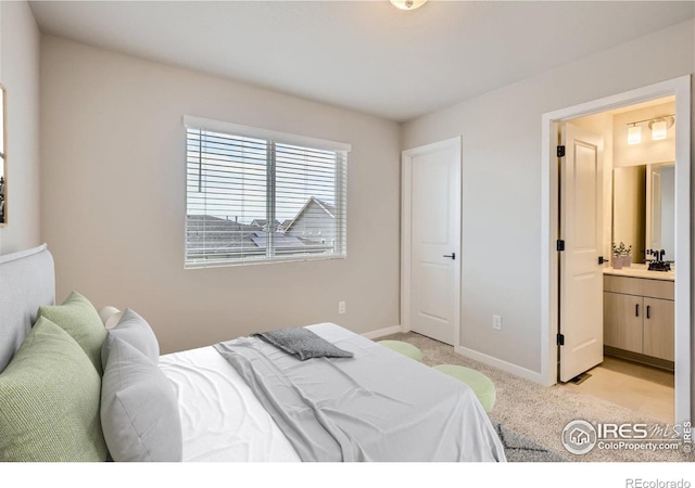 bedroom featuring light carpet, connected bathroom, and sink