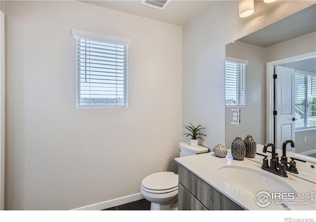 bathroom featuring a wealth of natural light, vanity, and toilet