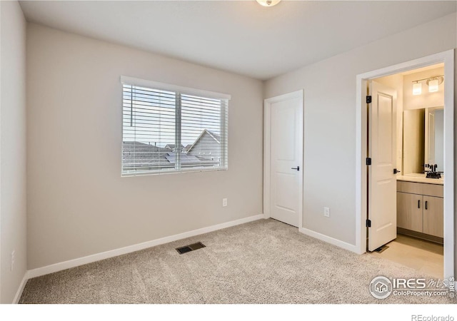 unfurnished bedroom with connected bathroom, sink, and light colored carpet