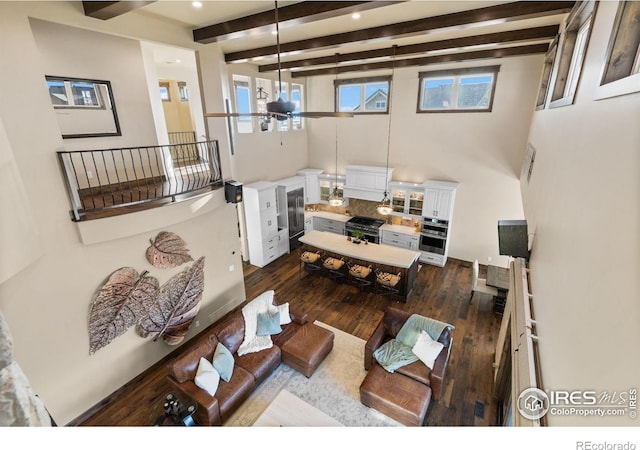 living room with beam ceiling, dark wood-type flooring, and a high ceiling