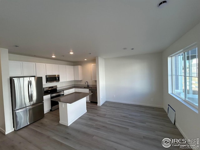 kitchen featuring white cabinetry, a center island, sink, stainless steel appliances, and light hardwood / wood-style flooring