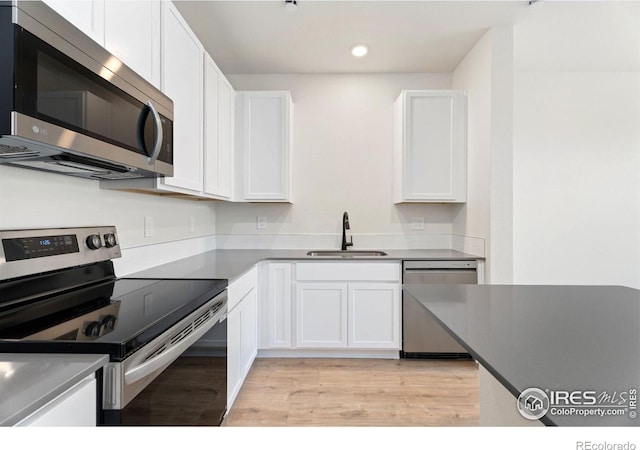 kitchen with white cabinetry, sink, stainless steel appliances, and light hardwood / wood-style floors