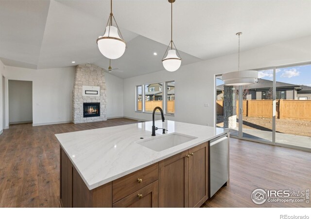 kitchen with stainless steel dishwasher, a center island with sink, open floor plan, and a sink