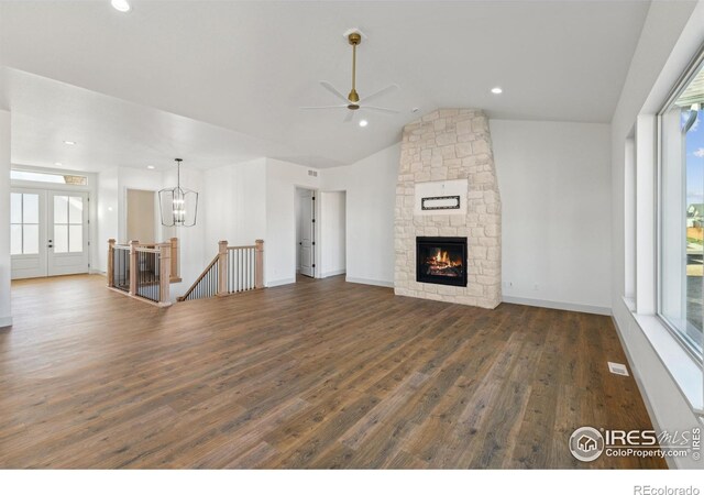 unfurnished living room with baseboards, lofted ceiling, dark wood-style floors, a fireplace, and ceiling fan with notable chandelier