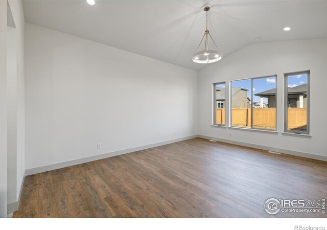 spare room featuring lofted ceiling, baseboards, wood finished floors, and recessed lighting