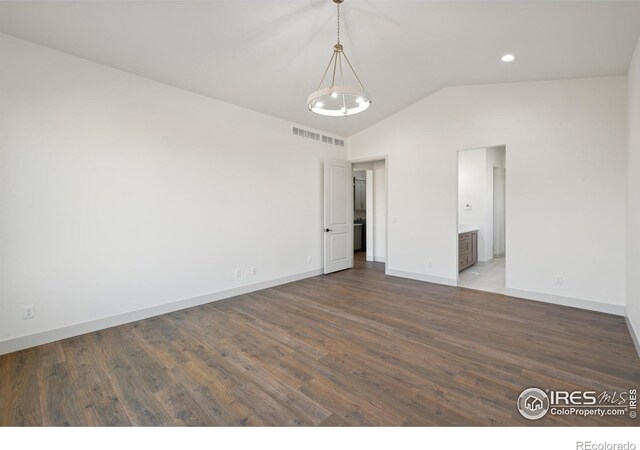 empty room with baseboards, visible vents, vaulted ceiling, and dark wood-style flooring