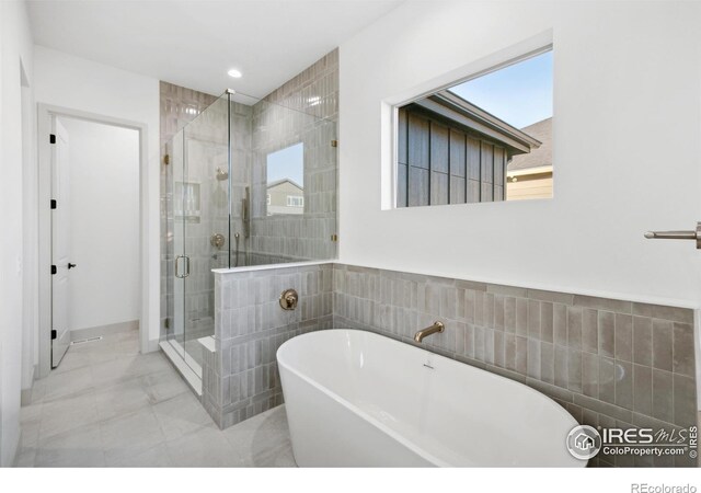 bathroom featuring a stall shower, a freestanding tub, tile walls, and recessed lighting