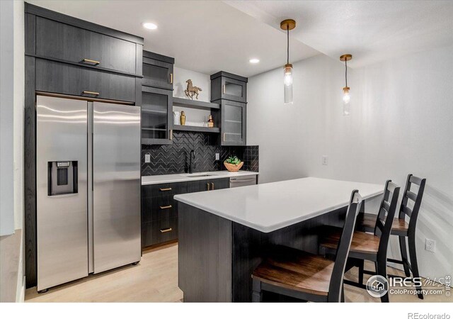 kitchen with built in fridge, a sink, hanging light fixtures, light countertops, and open shelves