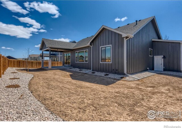 back of house with board and batten siding, fence private yard, and a shingled roof