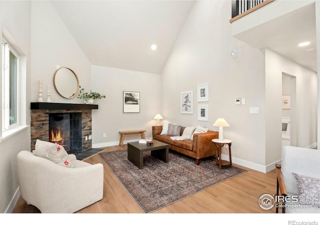 living room with high vaulted ceiling, a fireplace, and hardwood / wood-style floors