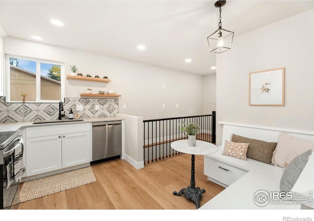 interior space featuring light hardwood / wood-style flooring, decorative light fixtures, white cabinetry, appliances with stainless steel finishes, and sink