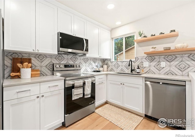 kitchen featuring appliances with stainless steel finishes, tasteful backsplash, white cabinets, and sink