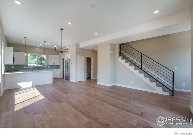 kitchen with white cabinets, light hardwood / wood-style floors, hanging light fixtures, a notable chandelier, and high end refrigerator