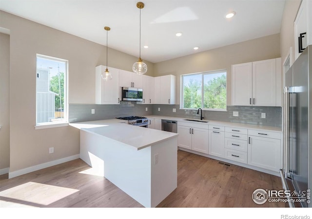 kitchen featuring pendant lighting, premium appliances, white cabinets, and kitchen peninsula