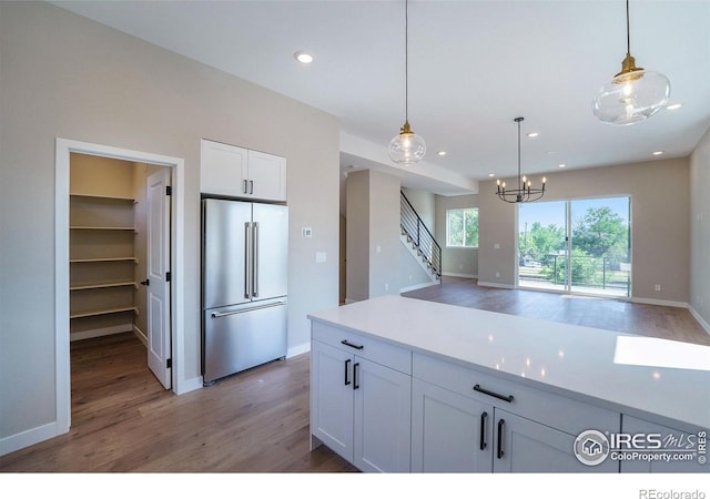 kitchen featuring decorative light fixtures, white cabinets, wood-type flooring, and high end fridge