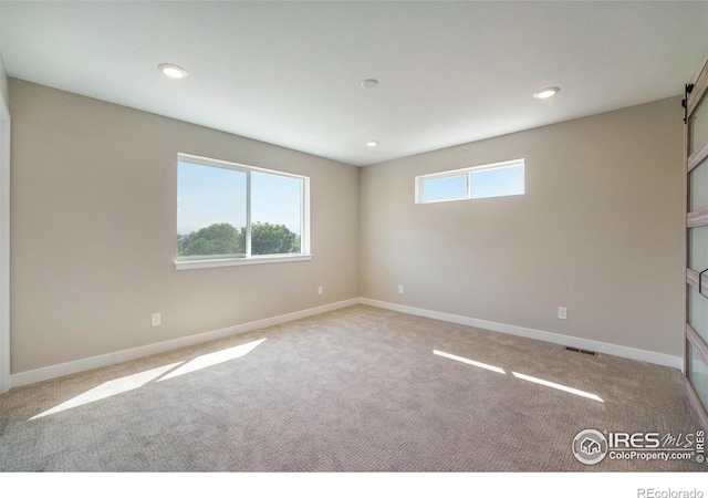 carpeted spare room featuring a barn door