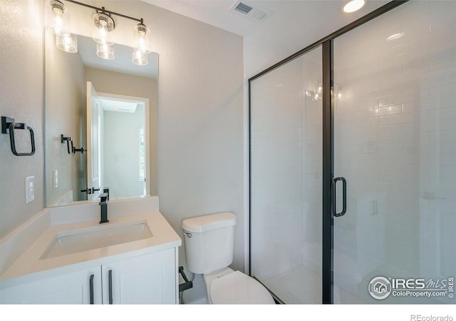 bathroom featuring toilet, a shower with shower door, and vanity