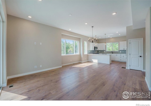 kitchen with pendant lighting, white cabinets, a center island, and a wealth of natural light