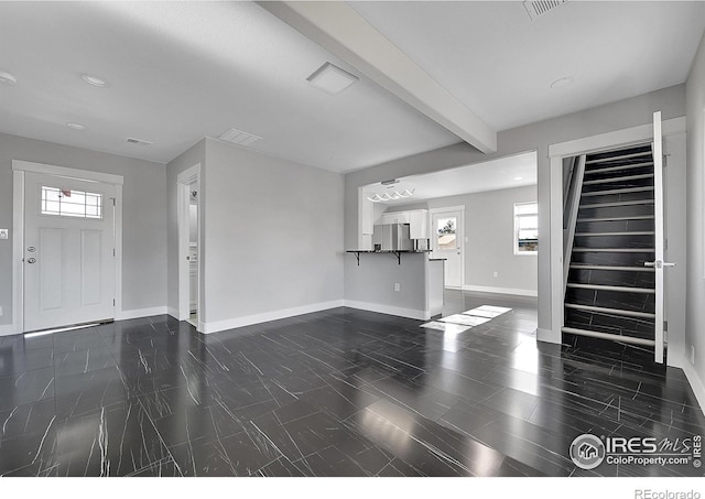 unfurnished living room with beam ceiling and a healthy amount of sunlight