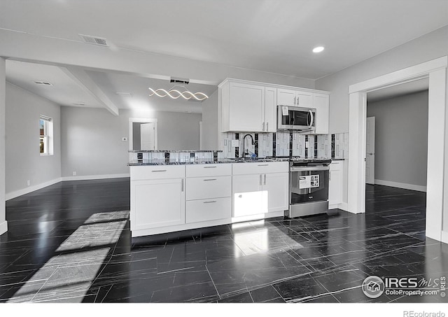 kitchen with decorative backsplash, dark stone countertops, white cabinetry, and stainless steel appliances