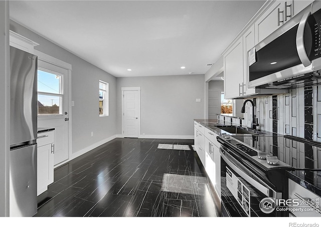 kitchen featuring appliances with stainless steel finishes, white cabinetry, and sink