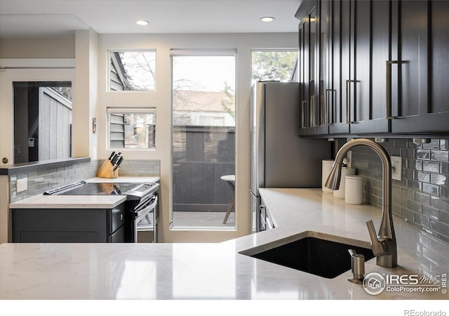 kitchen featuring decorative backsplash, stainless steel electric range oven, and sink