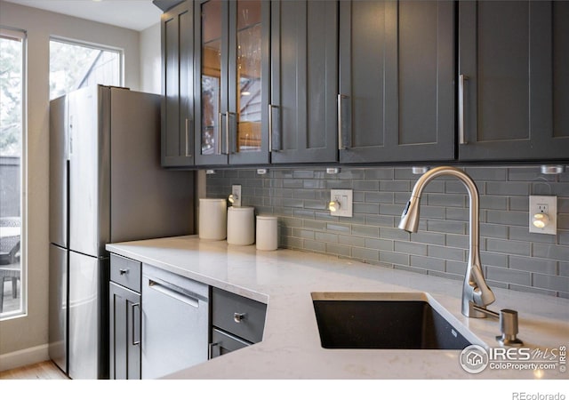 kitchen featuring tasteful backsplash, light stone counters, and sink