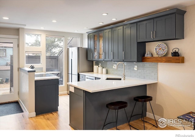 kitchen with kitchen peninsula, sink, a breakfast bar, and light wood-type flooring