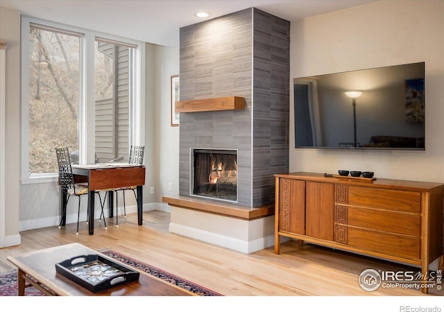 living room featuring light wood-type flooring and a tile fireplace