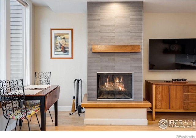 living room featuring light hardwood / wood-style flooring and a tiled fireplace