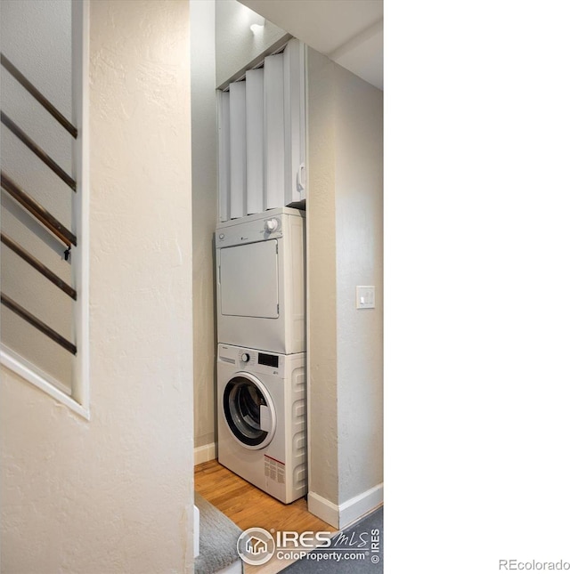 clothes washing area with stacked washer / dryer and light wood-type flooring