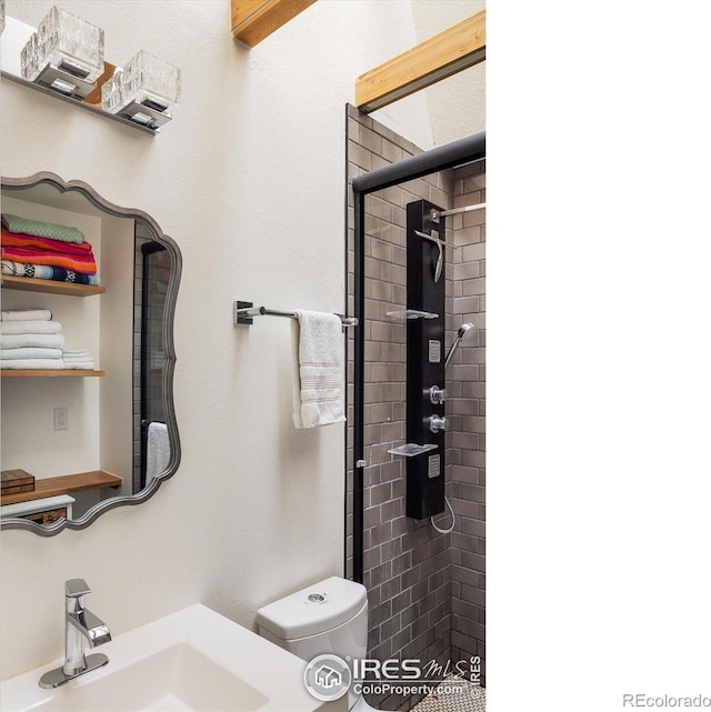 bathroom featuring sink, a shower with shower door, and toilet