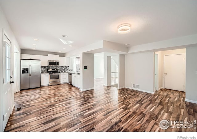 kitchen with backsplash, hardwood / wood-style floors, white cabinets, and appliances with stainless steel finishes