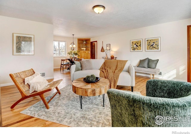 living room with hardwood / wood-style flooring, a textured ceiling, and a chandelier